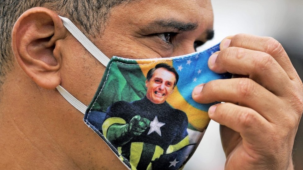 Homem de perfil com máscara estampada com imagem de Bolsonaro