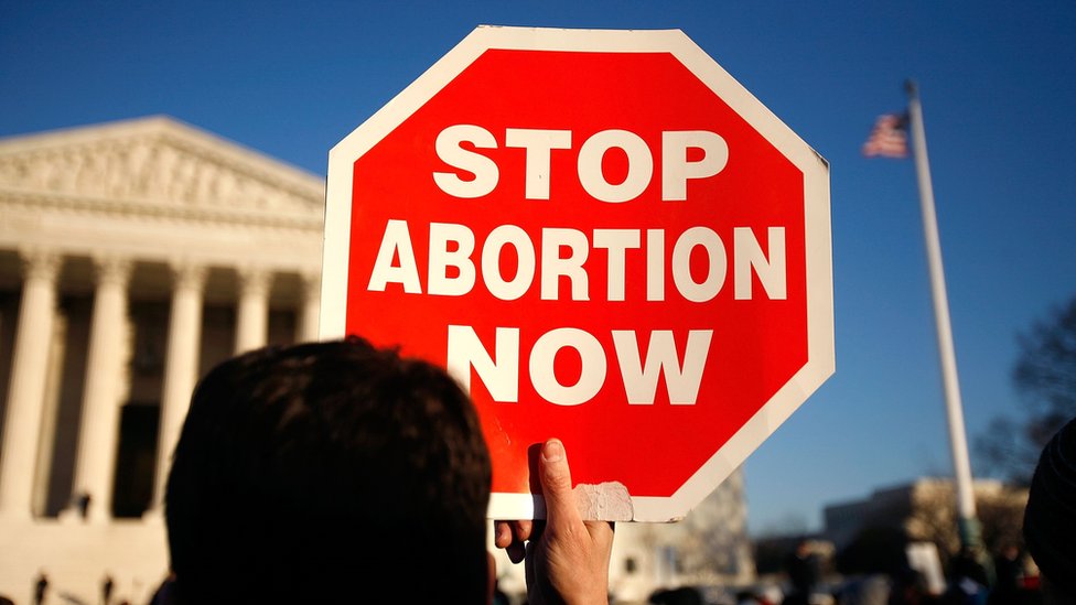 Участник кампании против абортов держит табличку с надписью «Прекратите аборты сейчас» у здания Верховного суда США