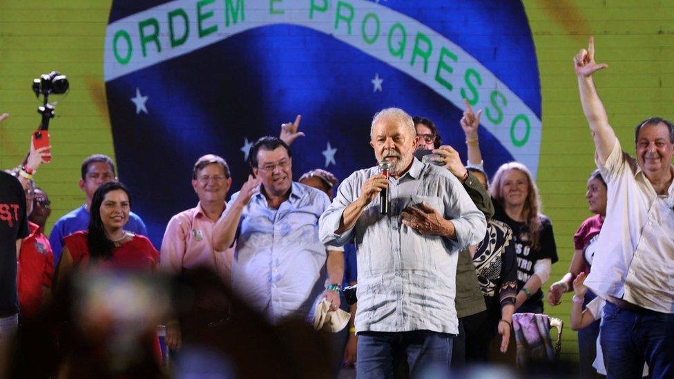 الرئيس البرازيلي السابق لولا يقف أمام العلم البرازيلي على الشاشة في تجمع انتخابي في ماناوس