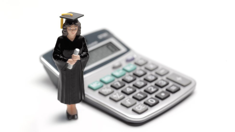 Una muñeca vestida de graduada y una calculadora