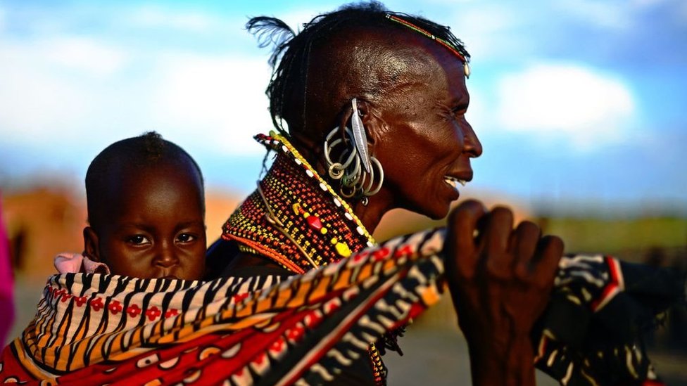 A woman from the Turkana tribe carries a baby on her back at the Lake Turkana Festival in Loiyangalani, near Lake Turkarna in Northern Kenya on May 19, 2012