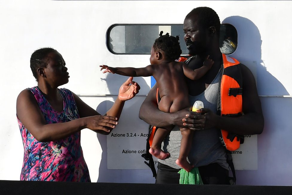 Una pareja con un niño de Libia espera para desembarcar del barco Guardia Costiera (Guardia Costera) de Italia en la isla Pelagia italiana de Lampedusa el 31 de julio de 2020.