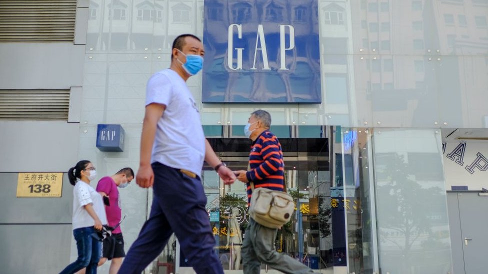 Покупатели выходят из магазина GAP в защитных масках в Пекине, Китай.