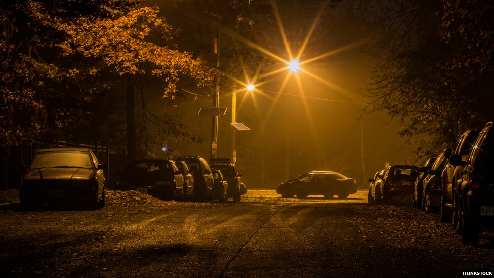 Автомобили, припаркованные в темноте под уличным фонарем