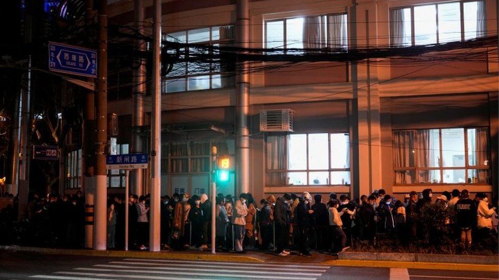 Personas formadas en un centro de pruebas de covid-19 en Shanghái