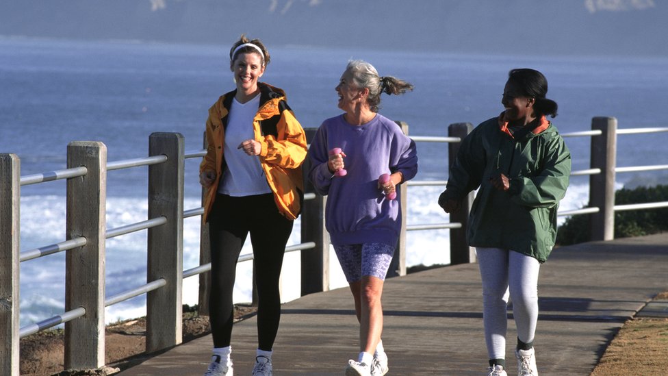 Tres mujeres andando con ritmo rápido por un embarcadero.