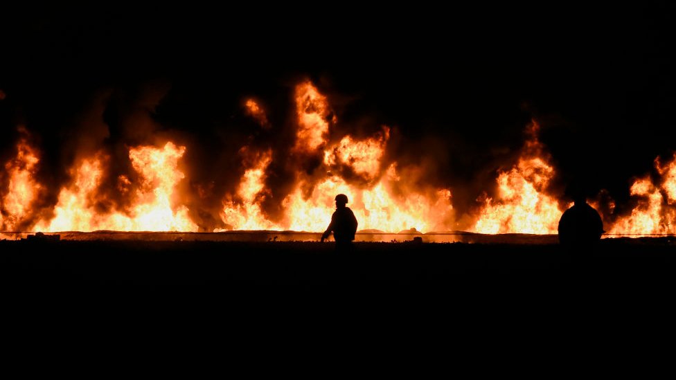 Bombero camina frente a la llamas.