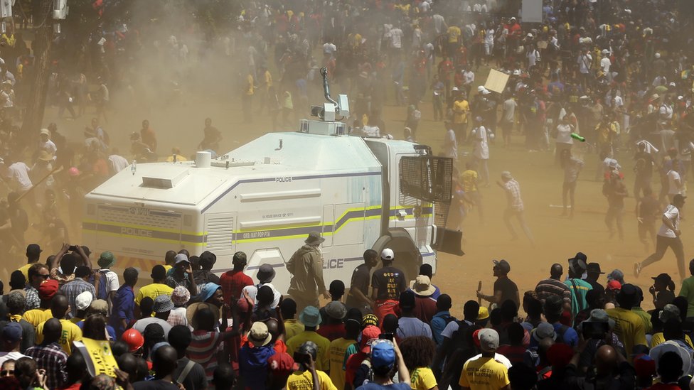 Полицейские водометы завалены протестующими студентами во время их акции протеста против увеличения платы за обучение у здания профсоюзов в Претории, Южная Африка