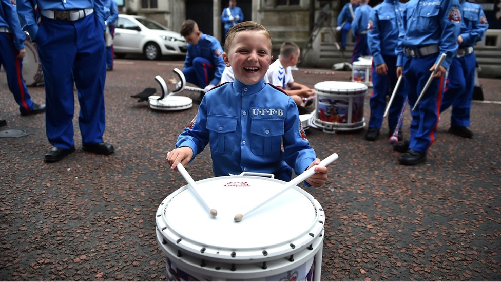 Мальчик в форме группы улыбается, играя на барабане