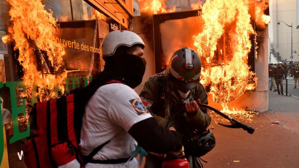 Пожарные пытаются потушить пламя после того, как протестующие сожгли рекламный щит во время акции протеста против капитального ремонта государственной пенсии в Париже, Франция, 11 января 2020 г.
