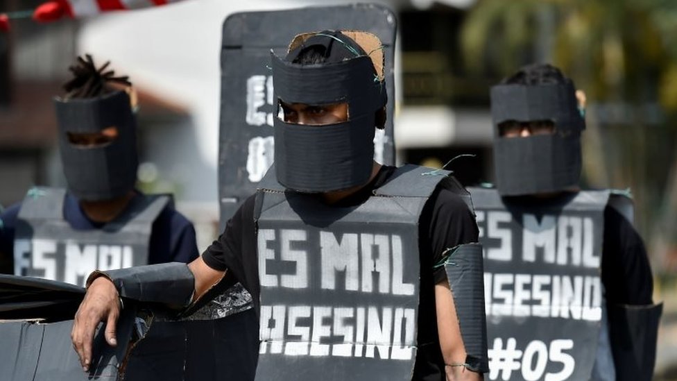 Студенты университета, одетые как члены Мобильной эскадрильи по борьбе с беспорядками (Эсмад), демонстрируют во время акции протеста против правительства президента Колумбии Ивана Дуке в Кали, Колумбия, 4 декабря 2019 г.