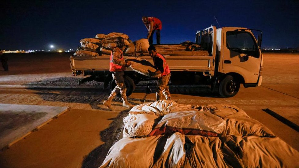 ثلاثة رجال يحملون شاحنة بالمساعدات المتجهة إلى سوريا.