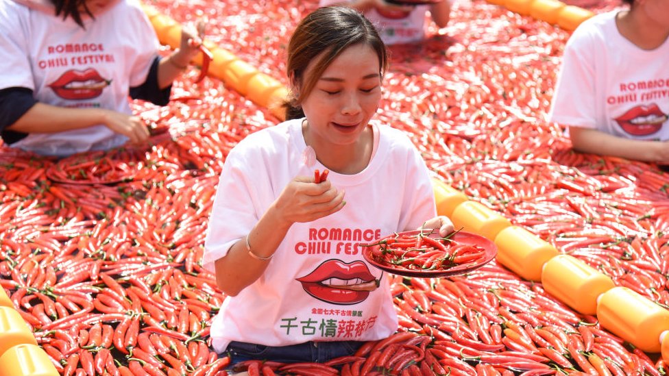 Una mujer come chiles en un concurso en China