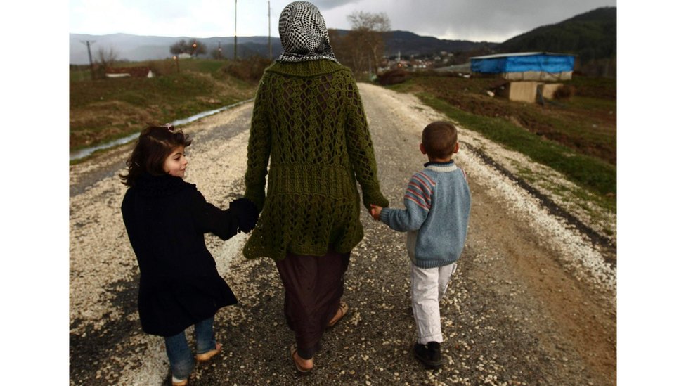 لاجئة سورية مع طفليها في تركيا