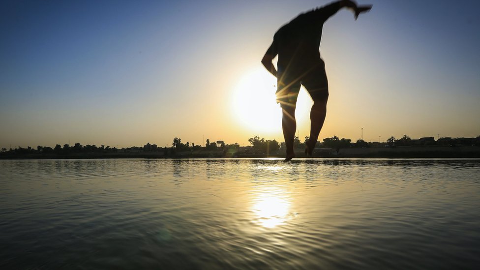 أشخاص يقفزون في نهر دجلة لتبريد أجسامهم خلال الجو اشديد الحرارة في بغداد في 18 يونيو/ حزيران 2022