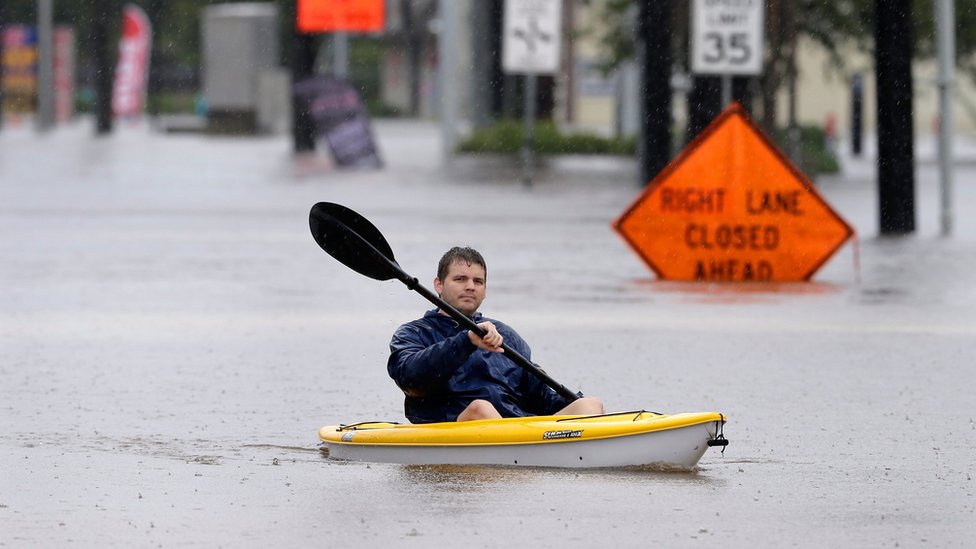 Las comunidades cercanas a las presas podrían sufrir más inundaciones como resultado de los desbordes. Un hombre trasladándose en canoa en un camino el norte de Houston.