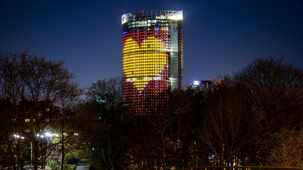 Башня DHL Post освещена, чтобы поблагодарить рабочих во время кризиса с коронавирусом 5 апреля 2020 г., Бонн, Германия