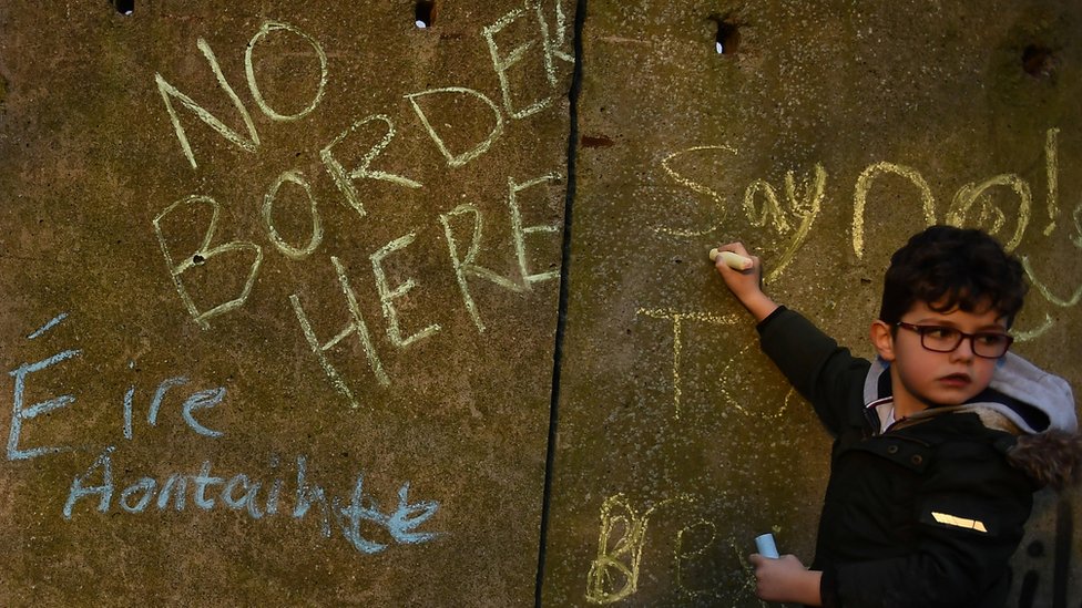 Мальчик пишет лозунги против Брексита на стене на ирландской границе