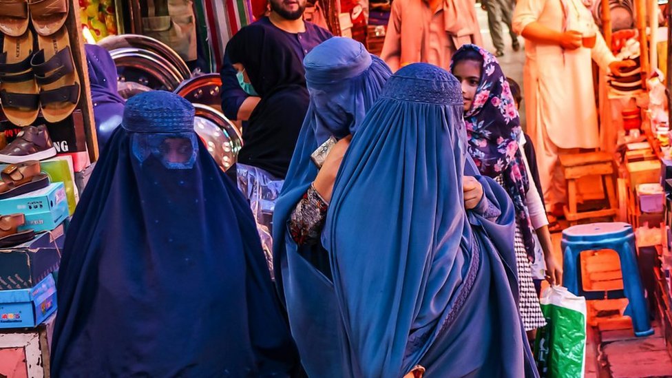 Perempuan memakai burkak di pasar di Kabul, Afghanistan.