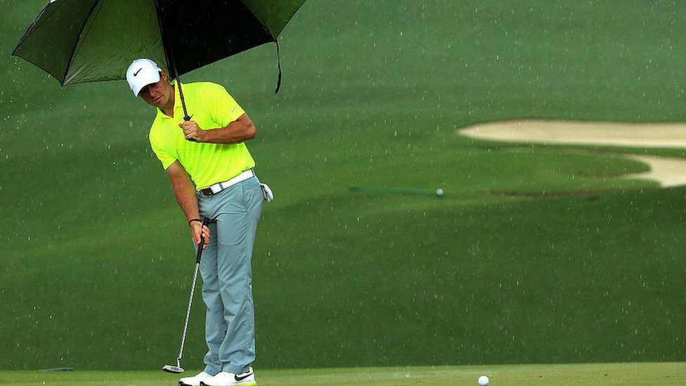 Рорли Макилрой играет в гольф под дождем.