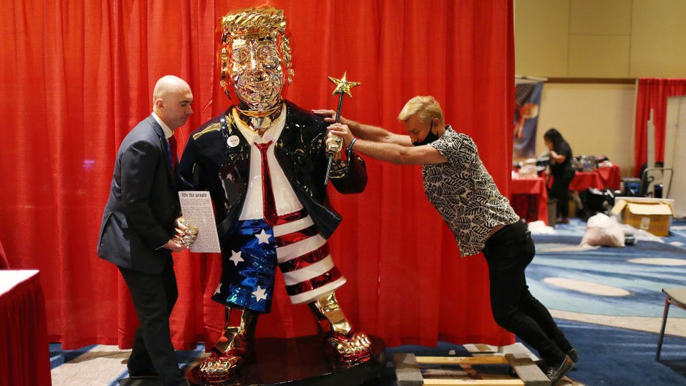 A golden statue of Donald Trump is seen being moved into CPAC conference