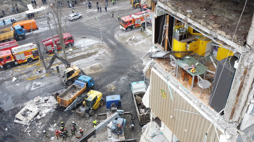 Wide shot of the kitchen with rescue vehicles seen on the street below