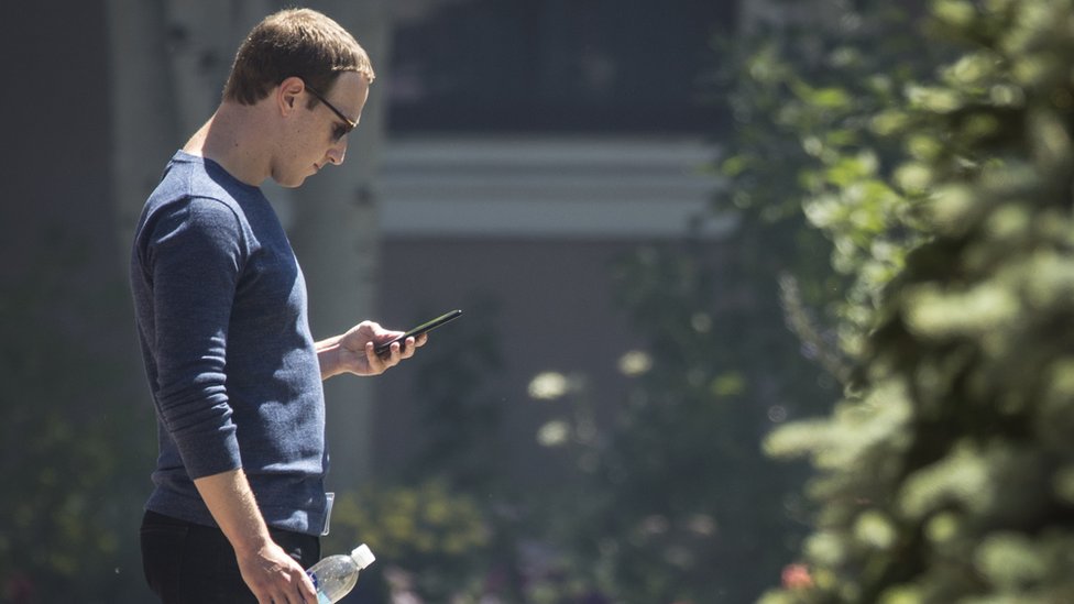   Mark Zuckerberg looks at his phone. 