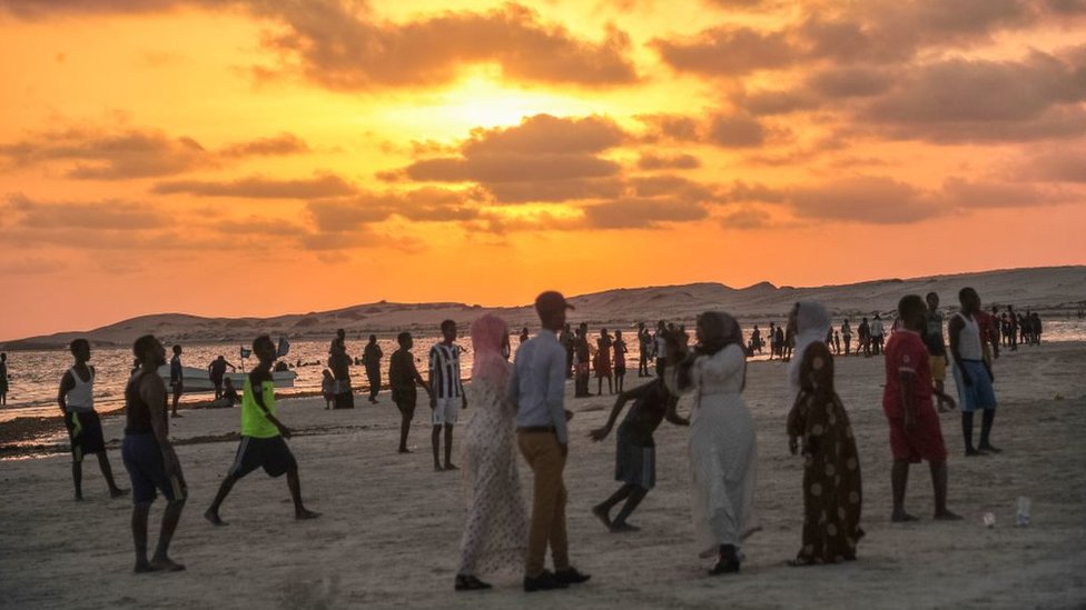 Сомалийцы гуляют по пляжу недалеко от Могадишо на закате