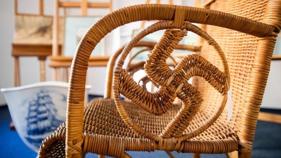 A wicker chair with swastika shape in arms