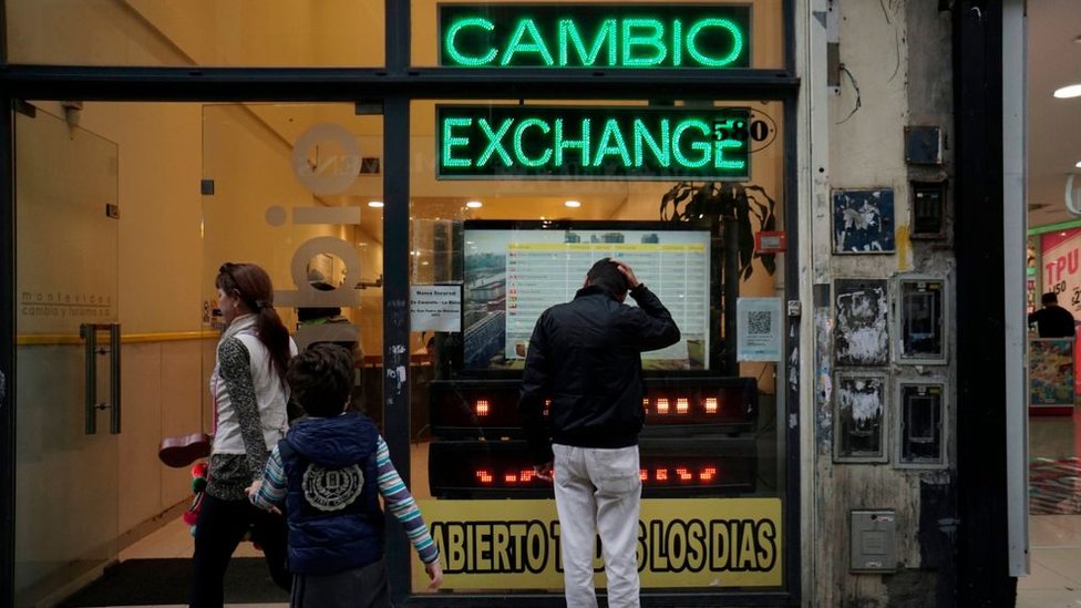 Un hombre mira la vitrina de una casa de cambios en Argentina.