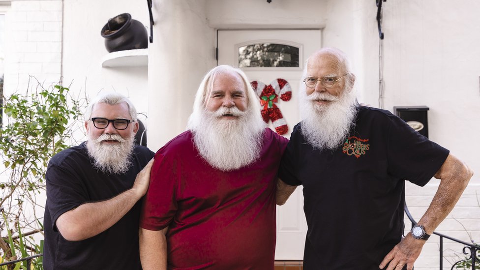 Tres intérpretes de Santa posan al frente de una casa en Miami