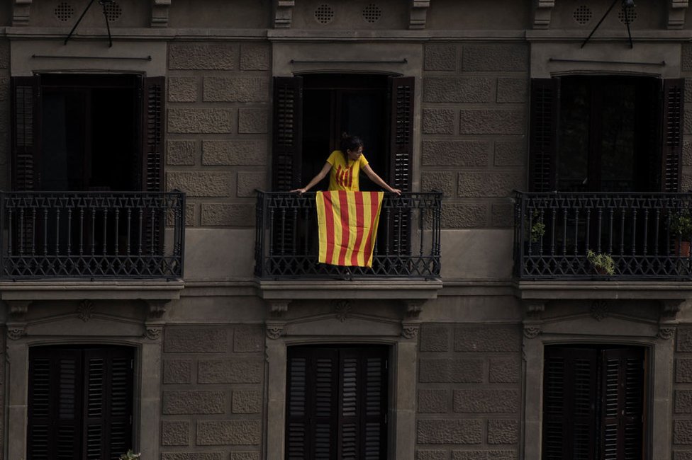 No son pocos los ciudadanos que se sienten en tierra de nadie ante la polarización de la discusión en Cataluña. Mujer en un balcón de Barcelona con la bandera catalana.