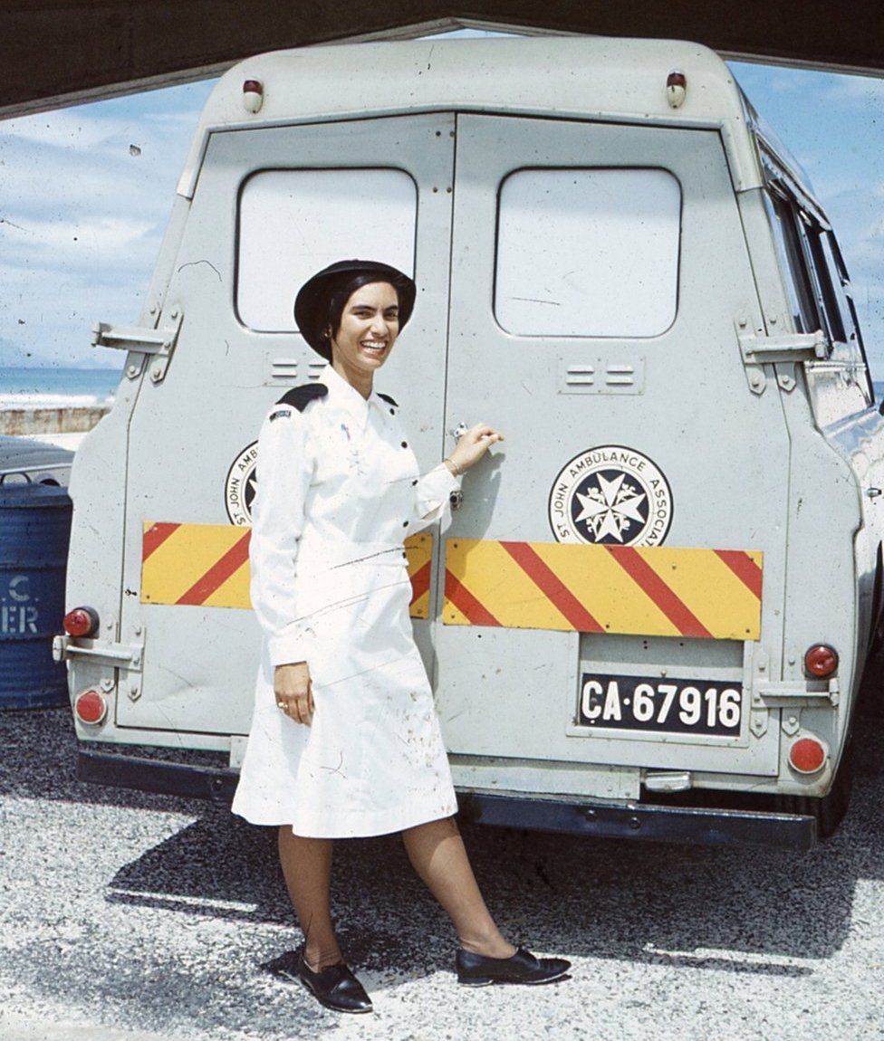 Маргарет в униформе медсестры перед машиной скорой помощи Святого Иоанна