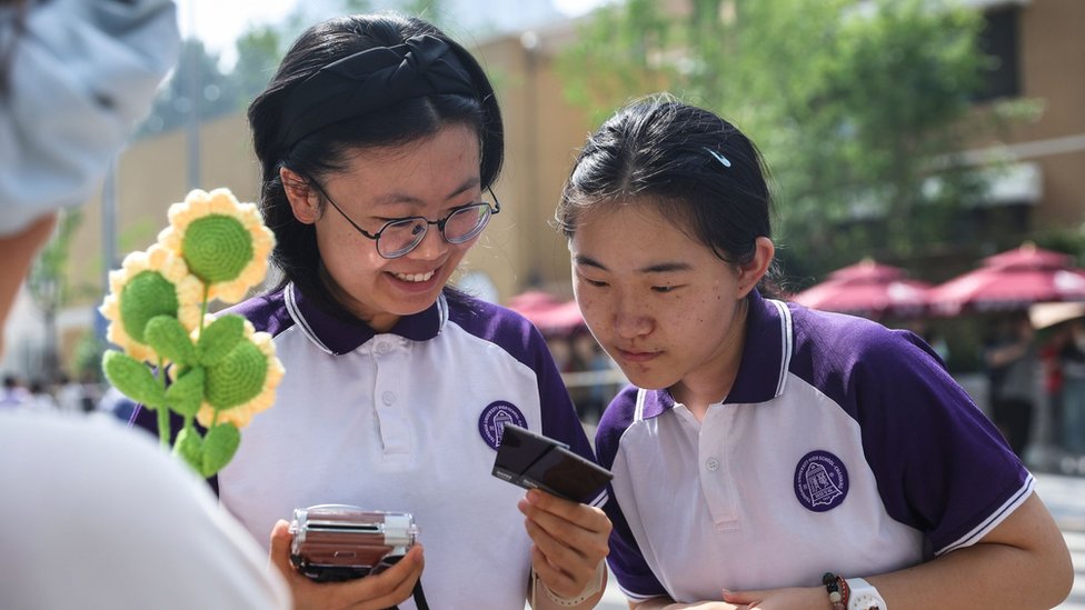 Students look at a photo outside a school on the last day of China's annual National College Entrance Examination in Beijing, China, 10 June 2024.