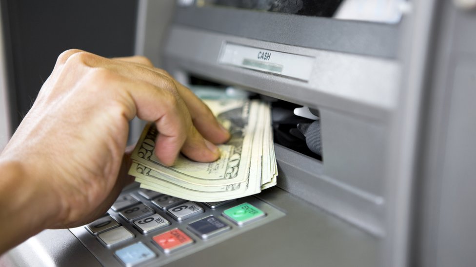 Persona recogiendo dinero de un cajero