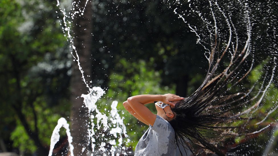 A woman refreshes herself in water at a square in Córdoba, Spain