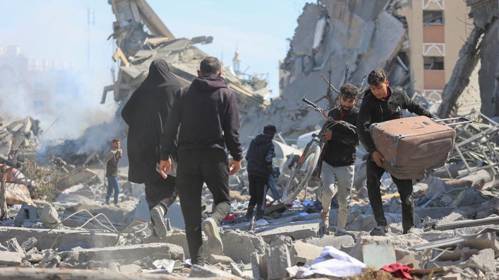 Palestinians walk through rubble in Khan Younis (13/03/24)