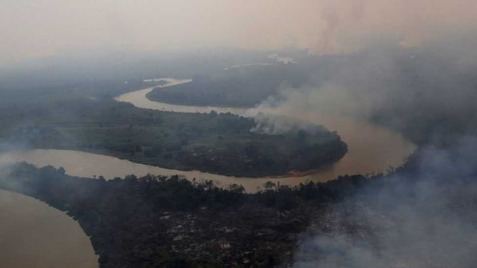 Vista aérea de rio no Pantanal, com florestas nas margens pegando fogo