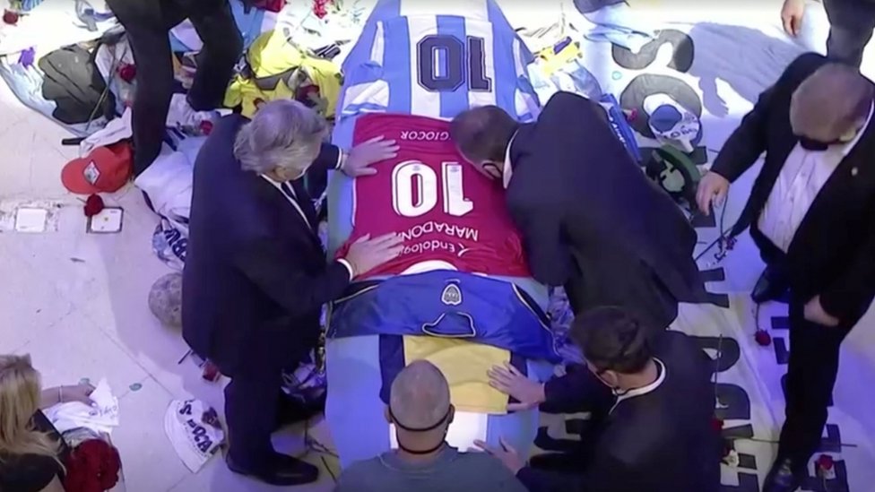 Argentina's President Alberto Fernandez places a football jersey on the casket of football legend Diego Maradona