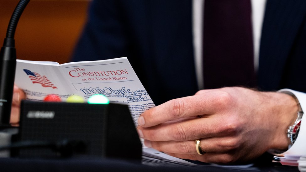 US Sen. Josh Hawley (R-MO) holds a small U.S. Constitution book while Supreme Court nominee Judge Amy Coney Barrett testifies before the Senate Judiciary Committee on Capitol Hill on 13 October 2020 in Washington, DC