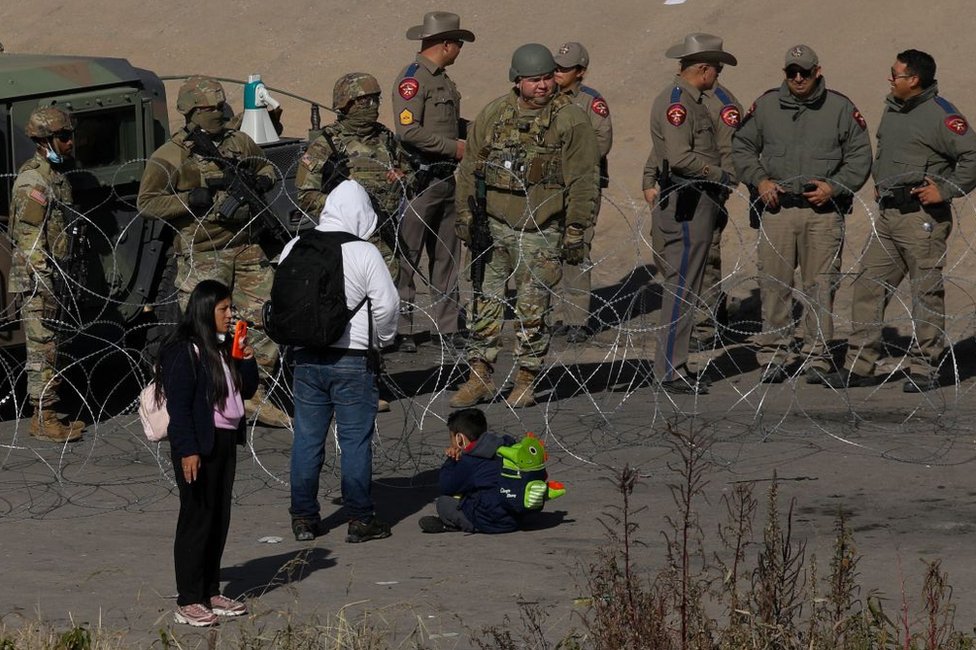 Migrantes piden la Guardia Nacional de Texas dejarles que se entreguen a la Patrulla Fronteriza en El Paso, Texas, Estados Unidos, justo al otro lado de la ciudad mexicana de Ciudad Juárez, el 20 de diciembre de 2022.