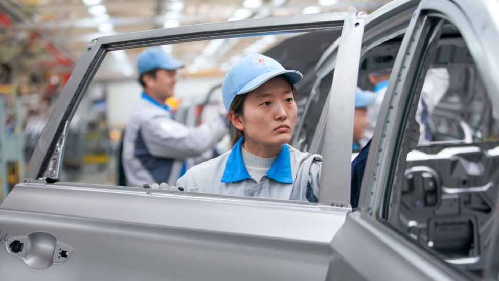عاملة في خط تجميع السيارات الكهربائية في مصنع دايون للسيارات في يونتشنغ، مقاطعة شانشي، الصين.
