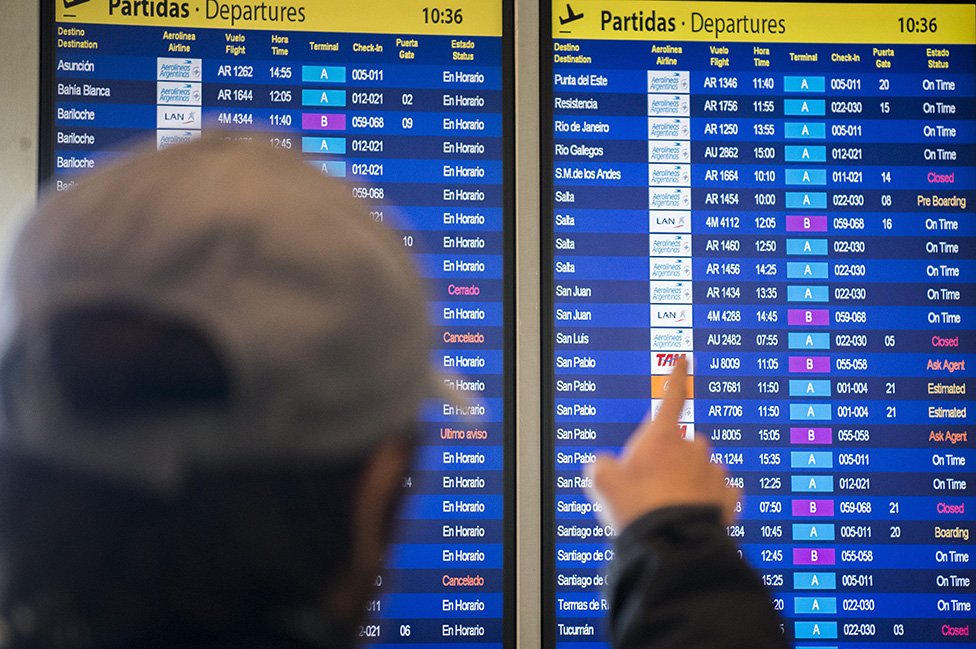 Passageiro olhando para lista de voos em painel em aeroporto na Argentina.