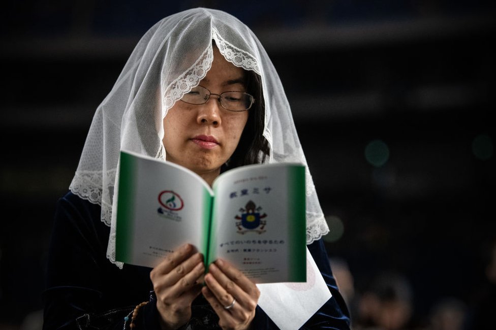 Una mujer católica lee una guía mientras espera a la misa masiva oficiada por el papa Francisco en Tokio el 25 de noviembre de 2019.