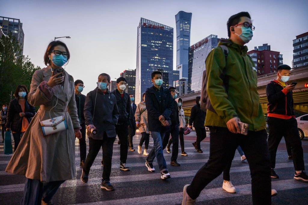 Trabajadores pendulares curzan una calle en Pekín durante la hora de alta congestión