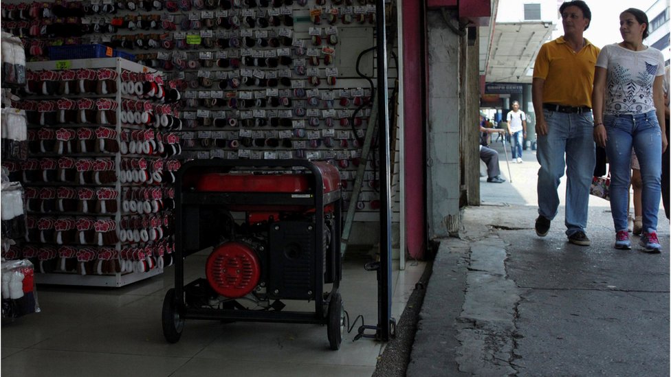 Una pareja pasa frente a una tienda con generador durante un apagón en San Cristóbal, Venezuela.