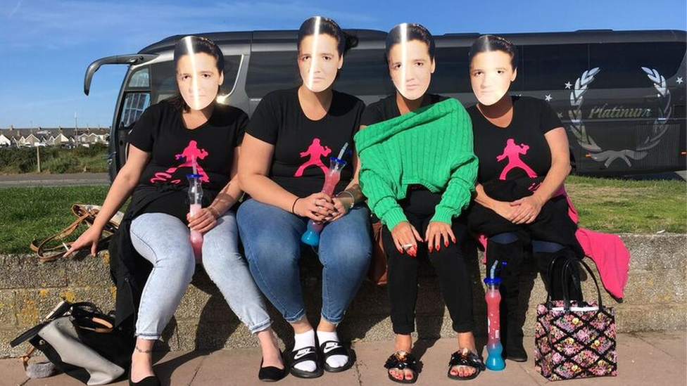 Четыре девушки сидели на тротуаре в Портколе в масках Элвиса