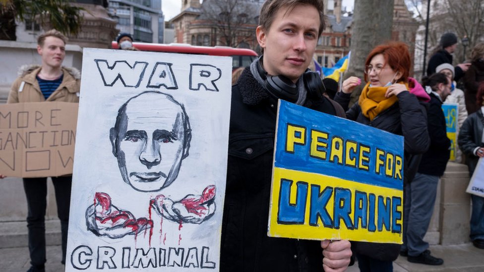 Un hombre con un cartel en el que se señala a Putin como criminal de guerra.