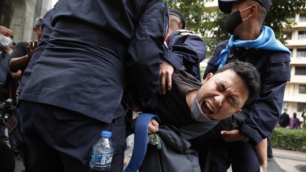 A pro-democracy protester reacts as he is being detained by police officers during a rally against the state of emergency at Ratchaprasong district in Bangkok, Thailand, 15 October 2020.