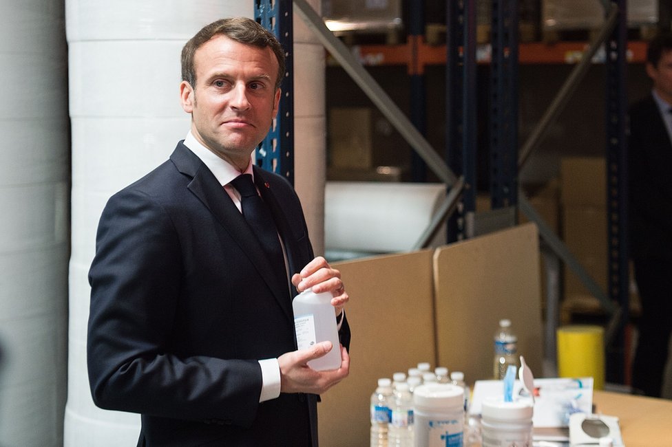 Президент Франции Эммануэль Макрон с бутылками дезинфицирующего средства для рук
